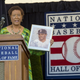 Former Philadelphia Inquirer sports columnist Claire Smith holds up a painting of former player Don Baylor — painted by her father — as she gives her acceptance speech after receiving the J.G. Taylor Spink Award from the Baseball Hall of Fame Saturday. (Clem Murray/Philadelphia Inquirer)